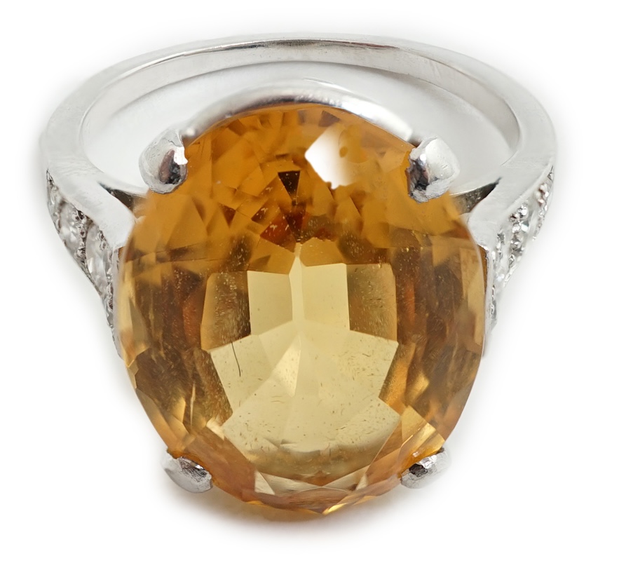 A 1940's platinum? and single stone oval cut imperial? topaz set dress ring, with ten stone graduated round cut diamond set shoulders